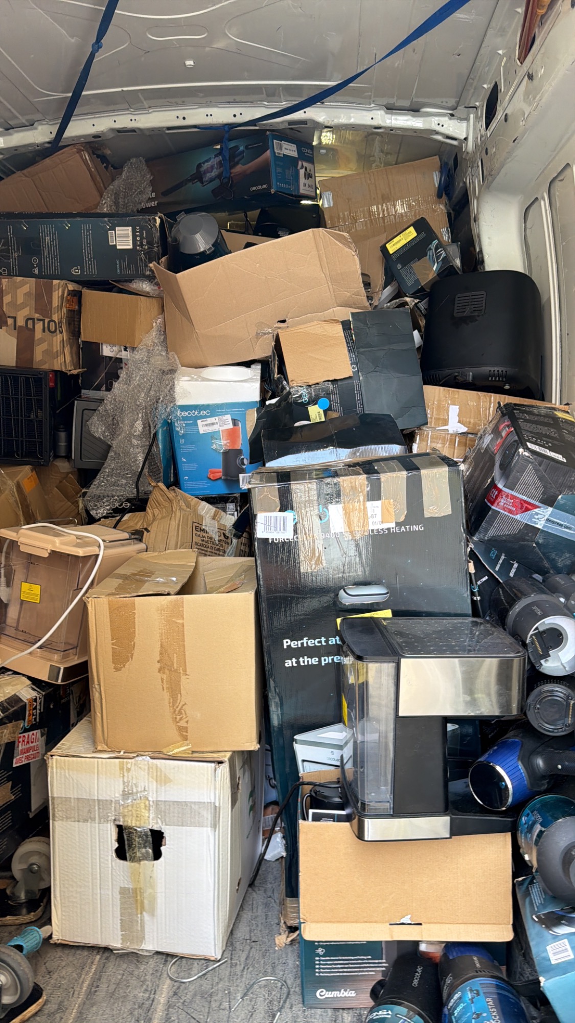 Cargas desordenadas de cajas y equipos en el interior de una furgoneta.